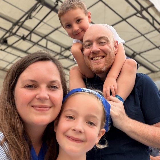 Dan, Julia and their two children, six and seven, smiling together at a summer event in Cumbria.
