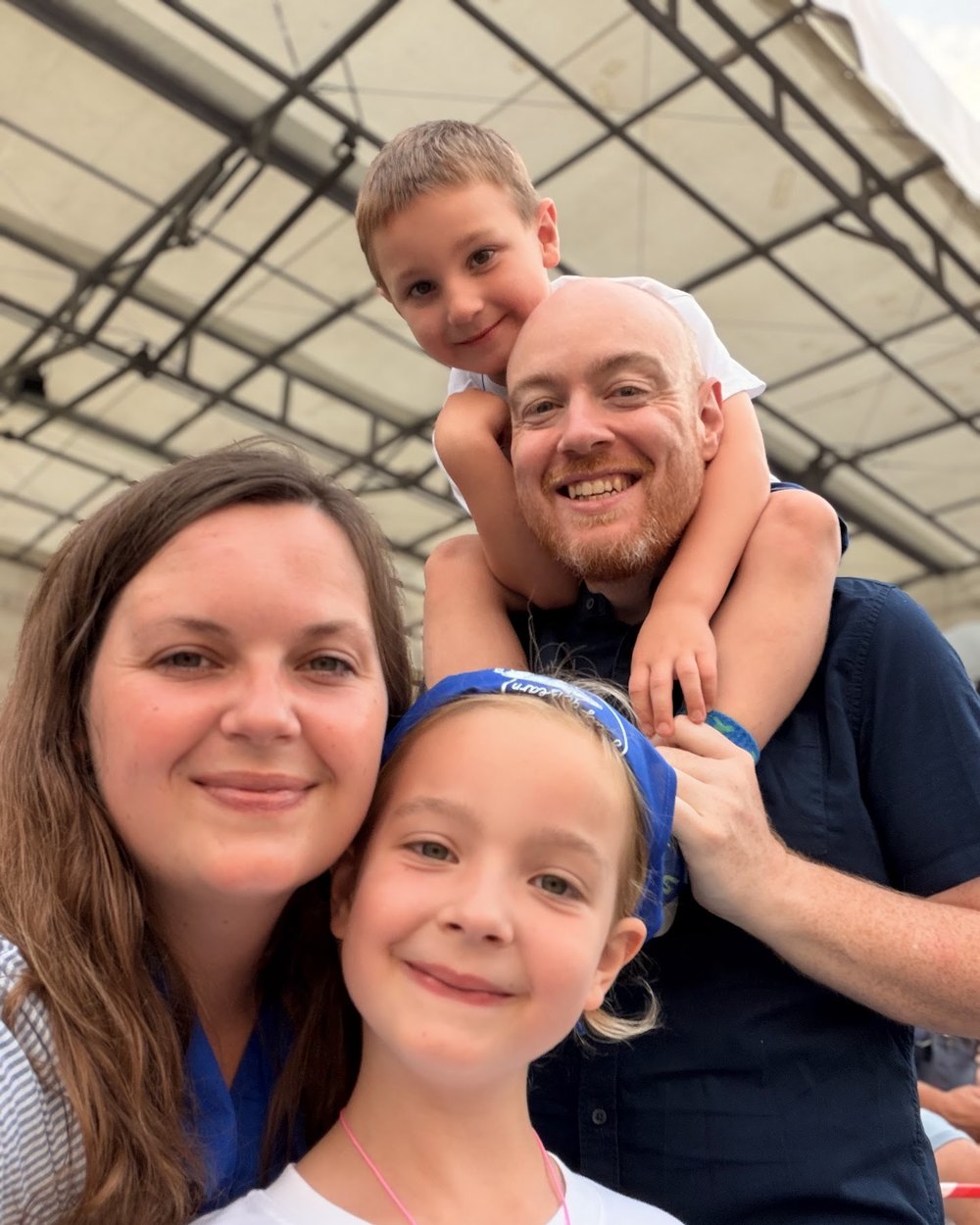 Dan, Julia and their two children, six and seven, smiling together at a summer event in Cumbria.