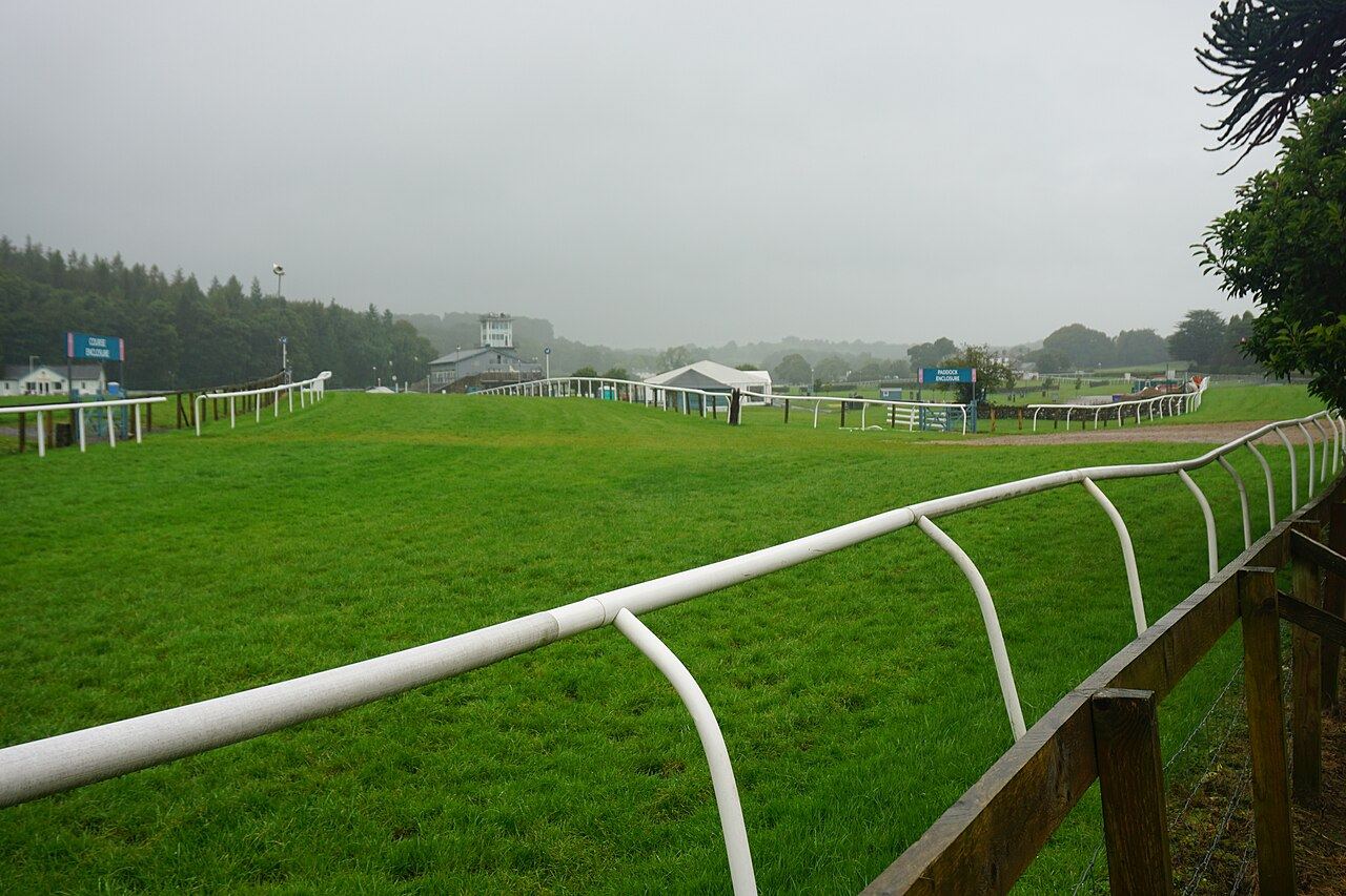 Cartmel Racecourse with the rails, grass track and wooded hills behind